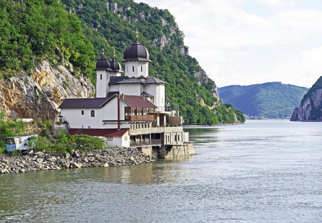 Yaz mevsiminde, yemyeşil dağların arasında yer alan Tuna Nehri geçidindeki manzaralı Ortodoks manastırı.