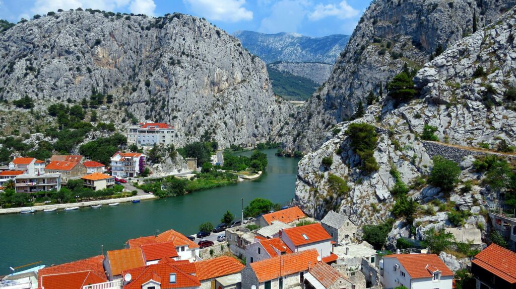 Hırvatistan’ın Omiš kentine ait nefes kesici manzara: sarp dağların arasından kıvrılarak geçen bir nehir ve kırmızı çatılı evler.