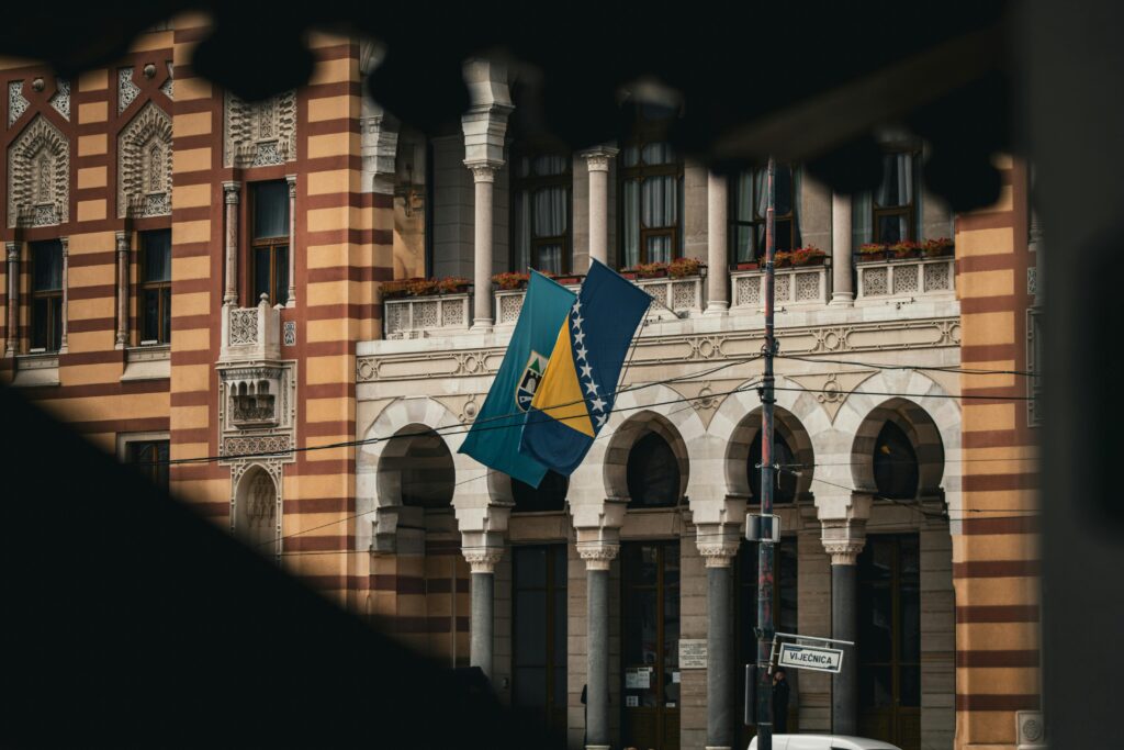 Bosna-Hersek bayrağıyla birlikte görünen, Saraybosna Belediye Binası’nın büyüleyici manzarası.